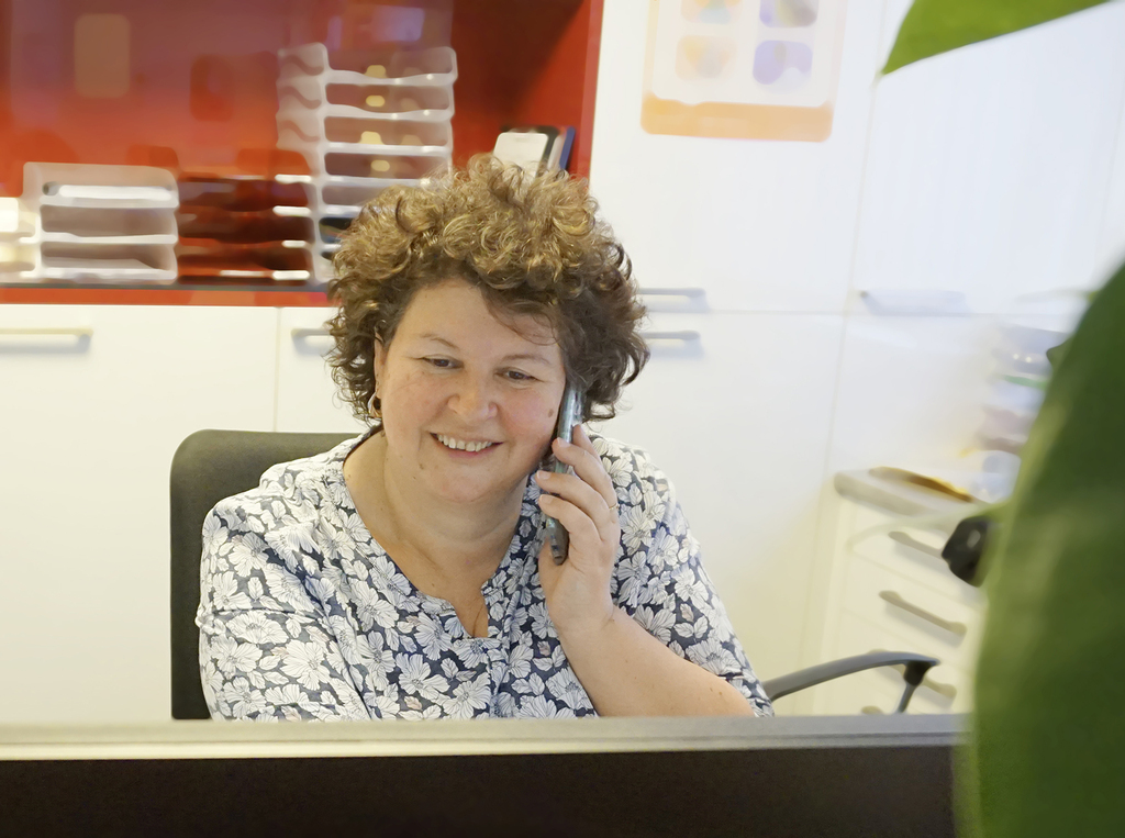 Sekretäring, lachend die gerade ein Telefongespräch führt.
